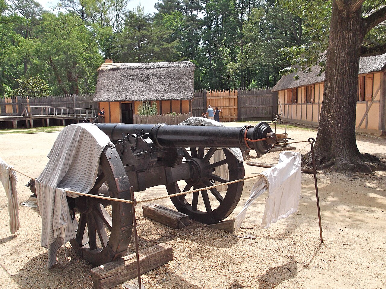 Reconstructed palisade wall, thatched-roof buildings, and period cannon at the Jamestown Settlement fort site in Virginia